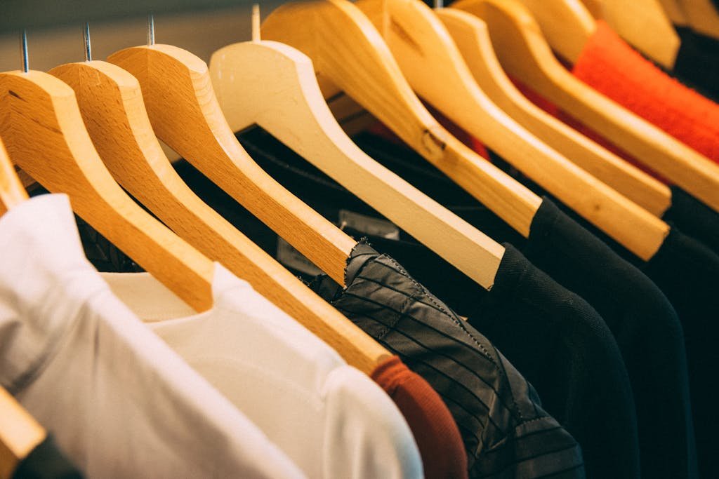 A close-up view Polo Shirts https://allhiphop.co.uk.com/of a row of clothes on wooden hangers, showcasing various fabrics and colors in a wardrobe setting.