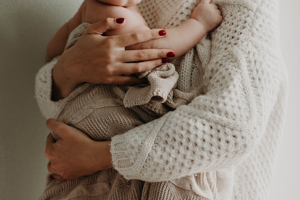 Close-up of a mother holding her LittleMinaxo in warm knitwear, conveying love and togetherness.