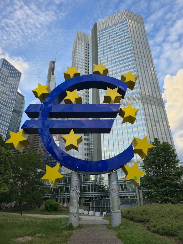 International Banking The Euro sculpture stands tall amid Frankfurt's modern skyscrapers, symbolizing financial strength.
