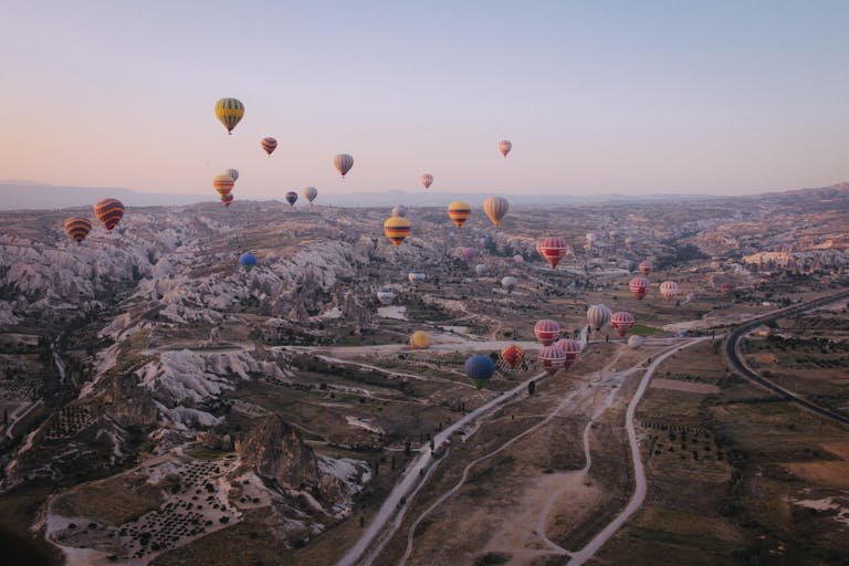 Air Hop Hot air balloons floating over Cappadocia's unique landscape at sunrise.